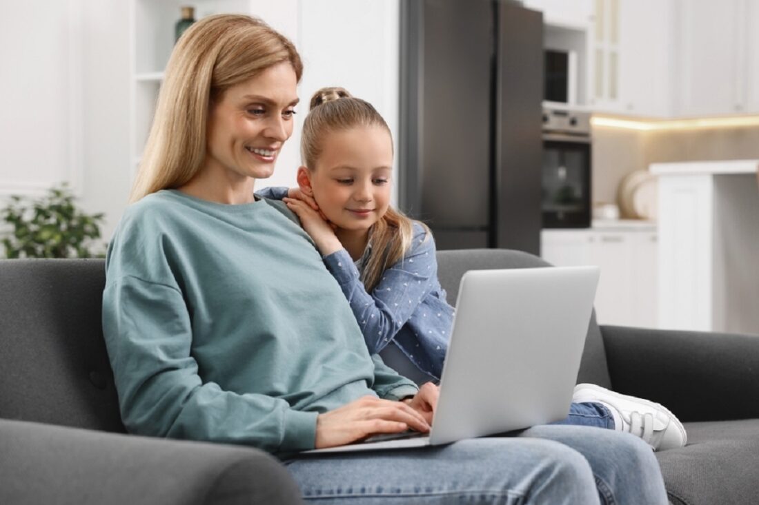 Happy,Woman,And,Her,Daughter,With,Laptop,On,Sofa,At