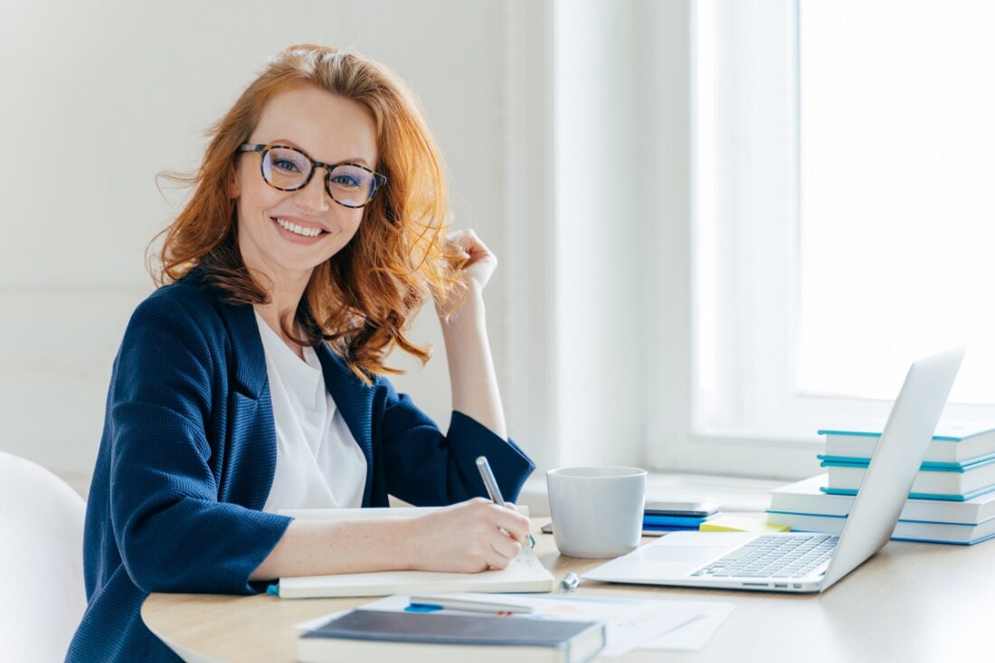 Sideways,Shot,Of,Prosperous,Businesswoman,With,Foxy,Hair,,Smiles,Positively,