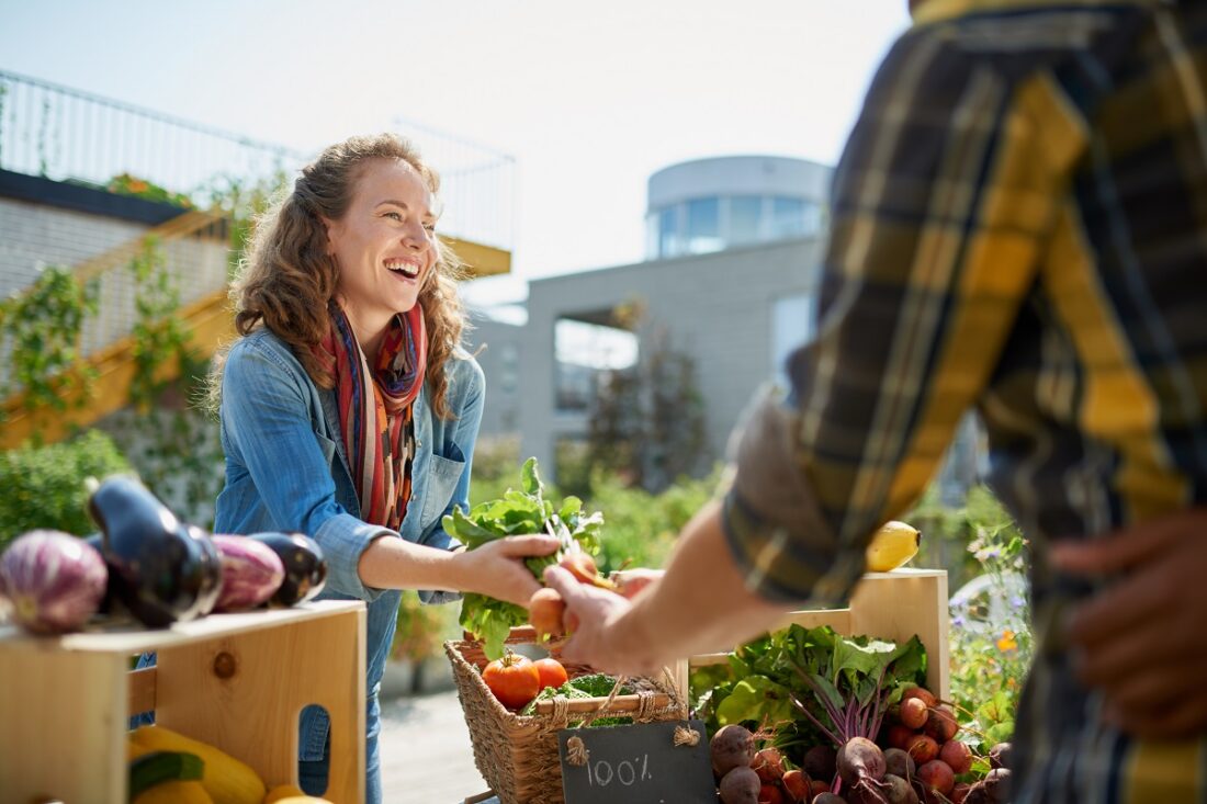 Friendly,Woman,Tending,An,Organic,Vegetable,Stall,At,A,Farmer's