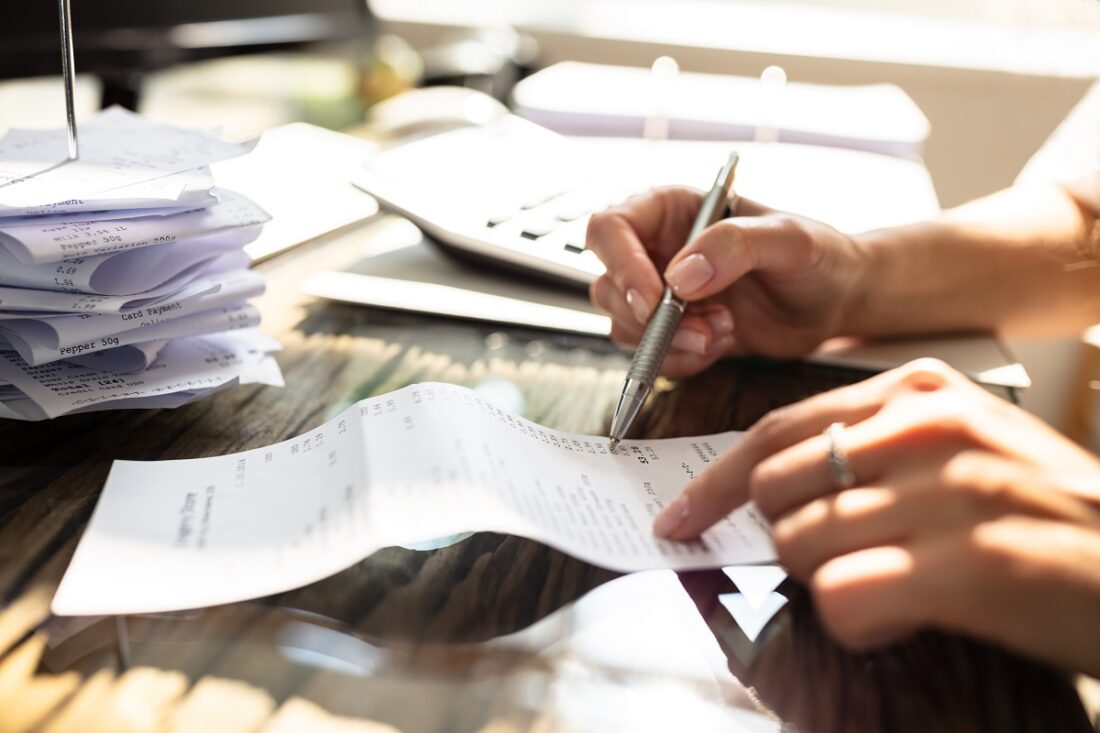 Close-up,Of,A,Businesswoman,Checking,Bill,Over,Wooden,Desk,In