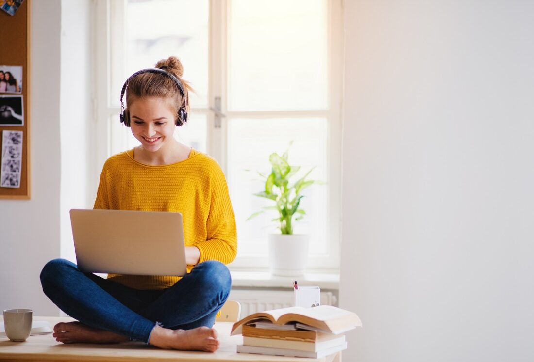 A,Young,Female,Student,Sitting,At,The,Table,,Using,Headphones