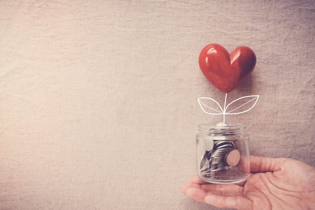 Hand,Holding,Heart,Plant,Jar,Growing,On,Money,Coins,,Saving,