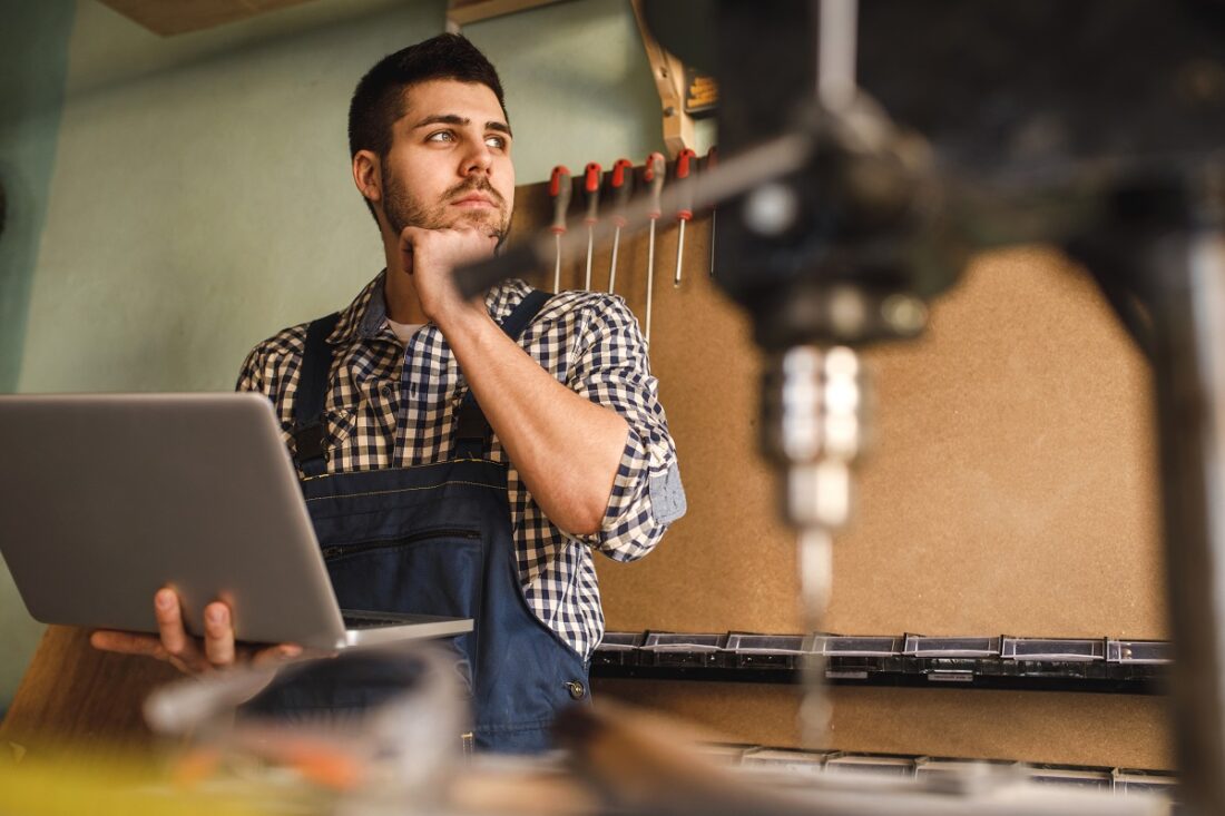 Shot,Of,A,Smiling,Carpenter,Using,Laptop,At,Work,In