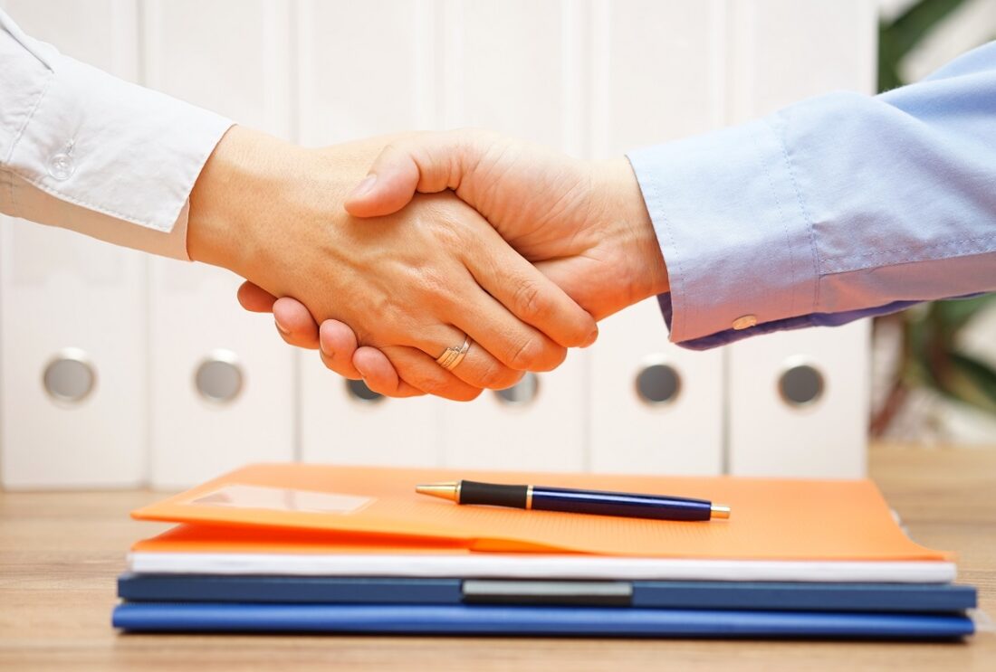 Business,Man,And,Woman,Are,Handshaking,Over,Documents,In,With