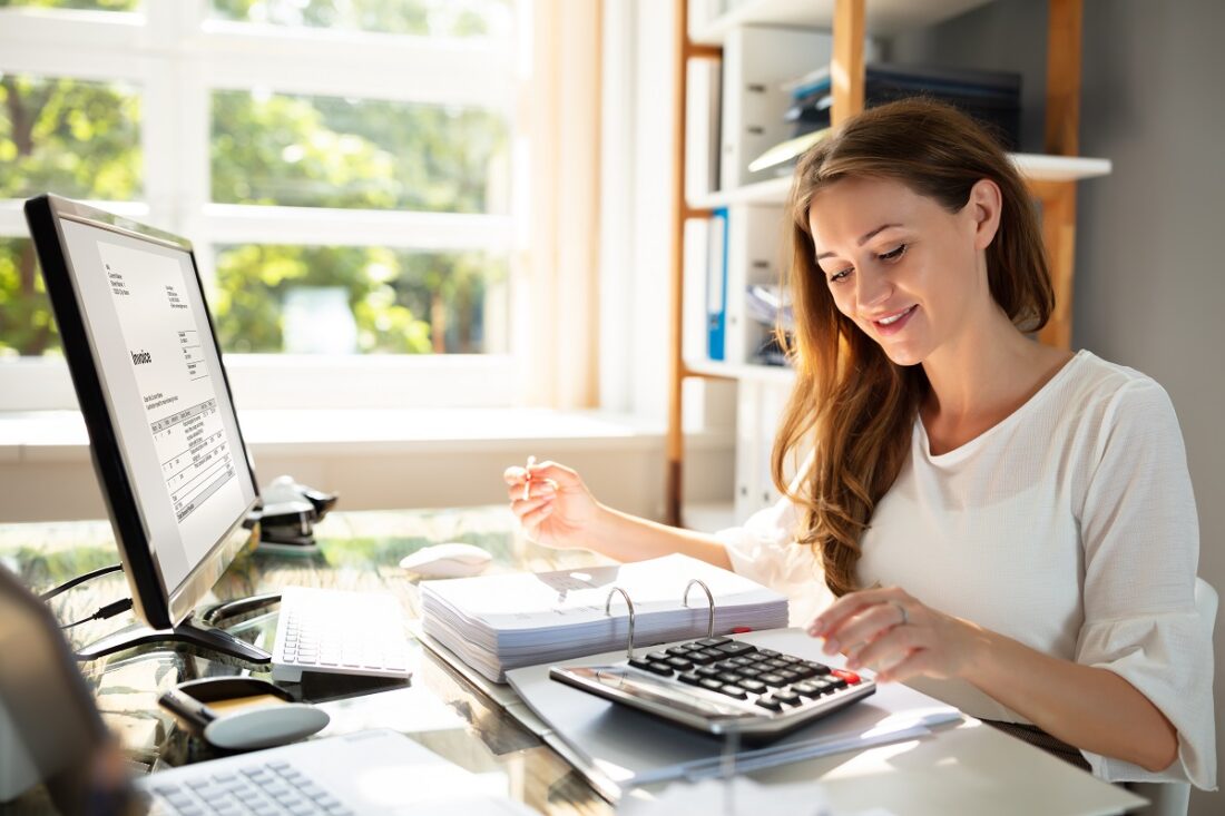 Smiling,Businesswoman's,Hand,Calculating,Bill,In,Office