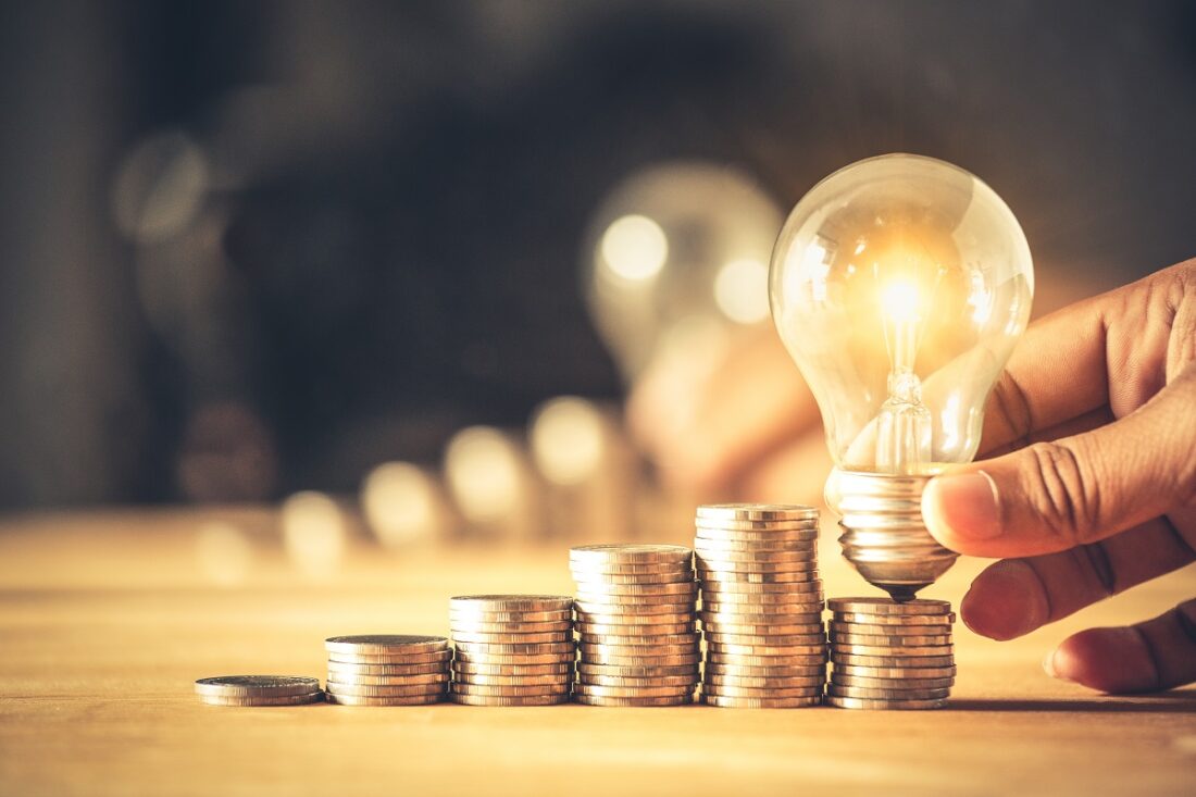 Hand,Holding,A,Light,Bulb,With,Coins,Stack.,Creative,Ideas