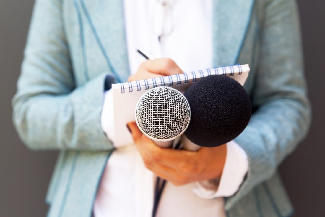 Female,Reporter,At,Press,Conference,,Writing,Notes,,Holding,Microphone