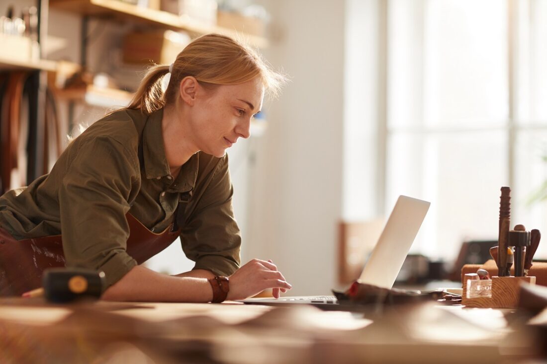 Warm,Toned,Portrait,Of,Successful,Female,Artisan,Using,Laptop,In