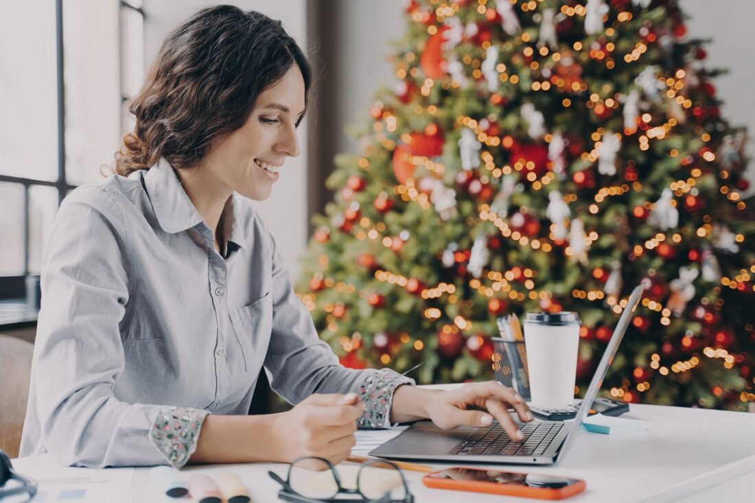 Side,View,Of,Smiling,Europian,Woman,Using,Laptop,At,Christmas