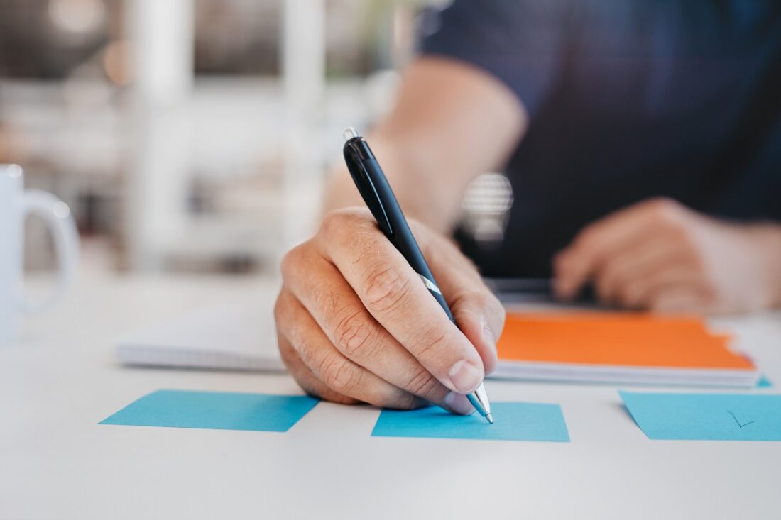 Close,Up,Image,Of,Business,Man,Writing,On,An,Adhesive