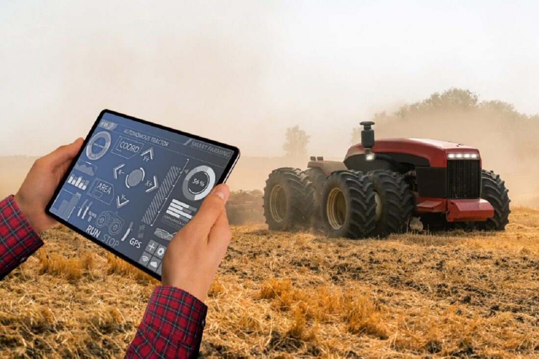 A,Farmer,With,Digital,Tablet,Controls,An,Autonomous,Tractor,On